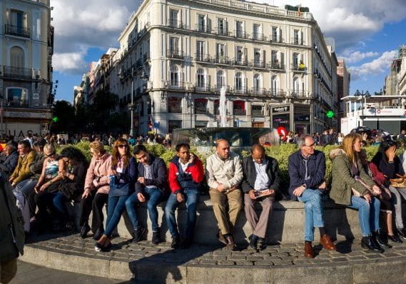 people sitting on a fountain at puerta del sol